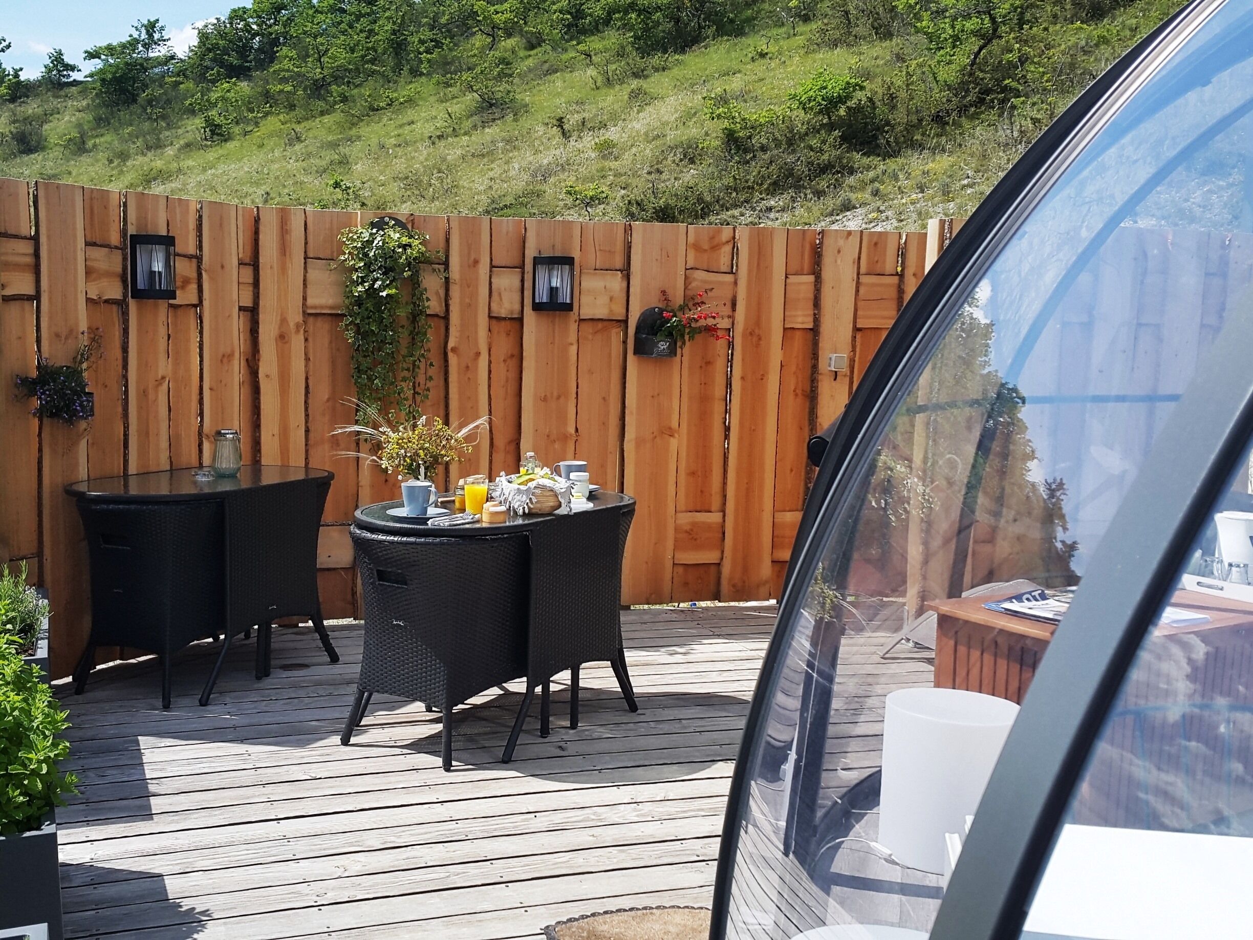 An outdoor patio with a wooden deck, two round tables, and chairs.