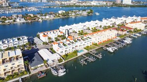 A marina with multiple boats docked, surrounded by residential buildings with balconies and a clear view of the water.