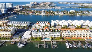 A marina with multiple boats docked, surrounded by residential buildings with balconies and a clear view of the ocean.