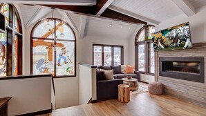 Uma sala de estar espaçosa com lareira, janelas amplas e um sofá moderno.