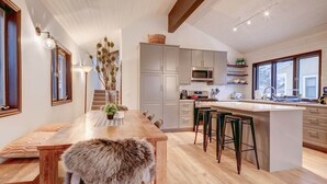 Uma cozinha moderna com uma ilha central, banquetas e um banco de madeira.
