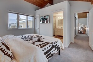 Une chambre à coucher comprenant un lit, une fenêtre, une porte donnant sur une salle de bain et un couloir.