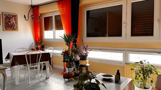 A dining area with a table set for two, surrounded by potted plants and a view of the city through large windows. - Bright and Spacious STUDIO,  40 sqm, cooling unit, Great View, Wifi, TV,  (Paris)