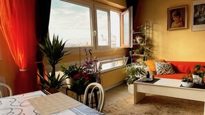 A living room with a sofa, a table with a patterned tablecloth, and a window with curtains. - Bright and Spacious STUDIO,  40 sqm, cooling unit, Great View, Wifi, TV,  (Paris)