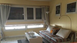 A bedroom with a bed, a sofa, a small table, and a window with blinds. - Bright and Spacious STUDIO,  40 sqm, cooling unit, Great View, Wifi, TV,  (Paris)