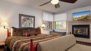 A bedroom with a bed, a fireplace, a ceiling fan, and a painting on the wall. - Tamarack - Steps to the Slopes + ASE Transportation (Snowmass Village)