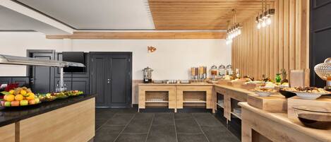 Una cocina moderna con techo de madera, armarios negros y una encimera larga con diversos alimentos y electrodomésticos.