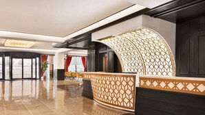 Un moderno vestíbulo de hotel con mostrador de recepción, ventanas amplias y piso de baldosas.