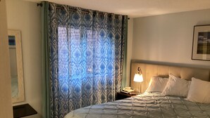 A hotel room with a large bed, a nightstand with a lamp, a trash bin, and a patterned curtain. - NordicVillageRESORT life@Storyland, very close to Attitash/Wildcat/Cranmore etc (Jackson)