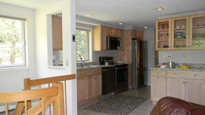 A modern kitchen with wooden cabinets, stainless steel appliances, and a dining area with a leather couch. - NordicVillageRESORT life@Storyland, very close to Attitash/Wildcat/Cranmore etc (Jackson)