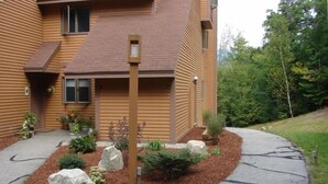 A modern building with a sloped roof and a landscaped front yard with rocks and plants. - NordicVillageRESORT life@Storyland, very close to Attitash/Wildcat/Cranmore etc (Jackson)