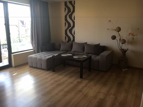 A modern living room with a sectional sofa, a coffee table, and a vase with dried flowers.