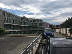 A multi-story building with balconies and a parking area.