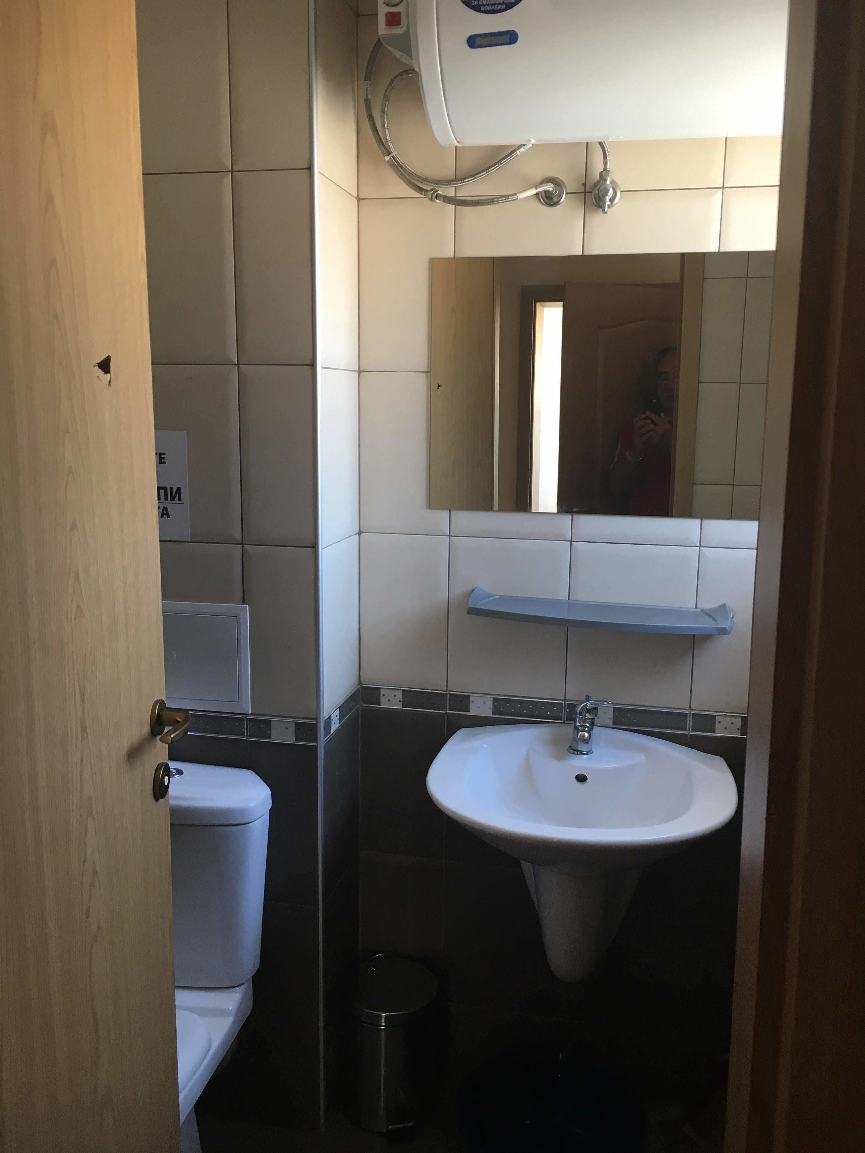Baño con inodoro, lavabo, espejo y ducha.