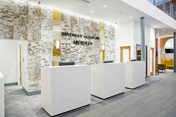 A reception area with a stone wall and a sign that reads "Sandman Signature Aberdeen." - Sandman Signature Aberdeen Hotel & Spa (Aberdeen)