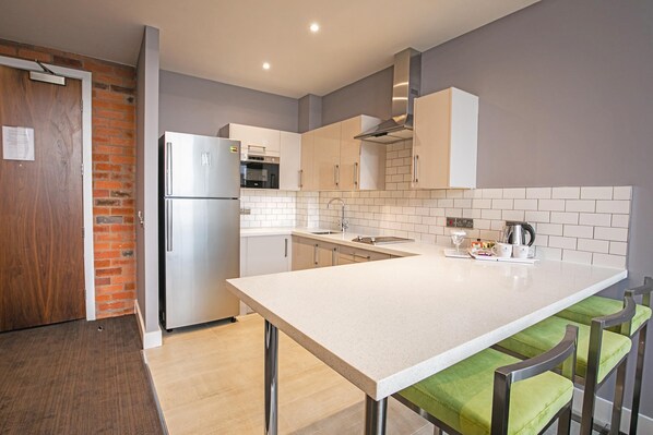 Une cuisine moderne dotée d’un grand îlot central, d’appareils électroménagers en acier inoxydable et d’un mur décoratif en briques.