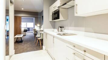 A modern kitchen with white cabinets, a built-in oven, and a window overlooking a dining area.