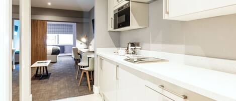 A modern kitchen with white cabinets, a built-in oven, and a window overlooking a dining area.
