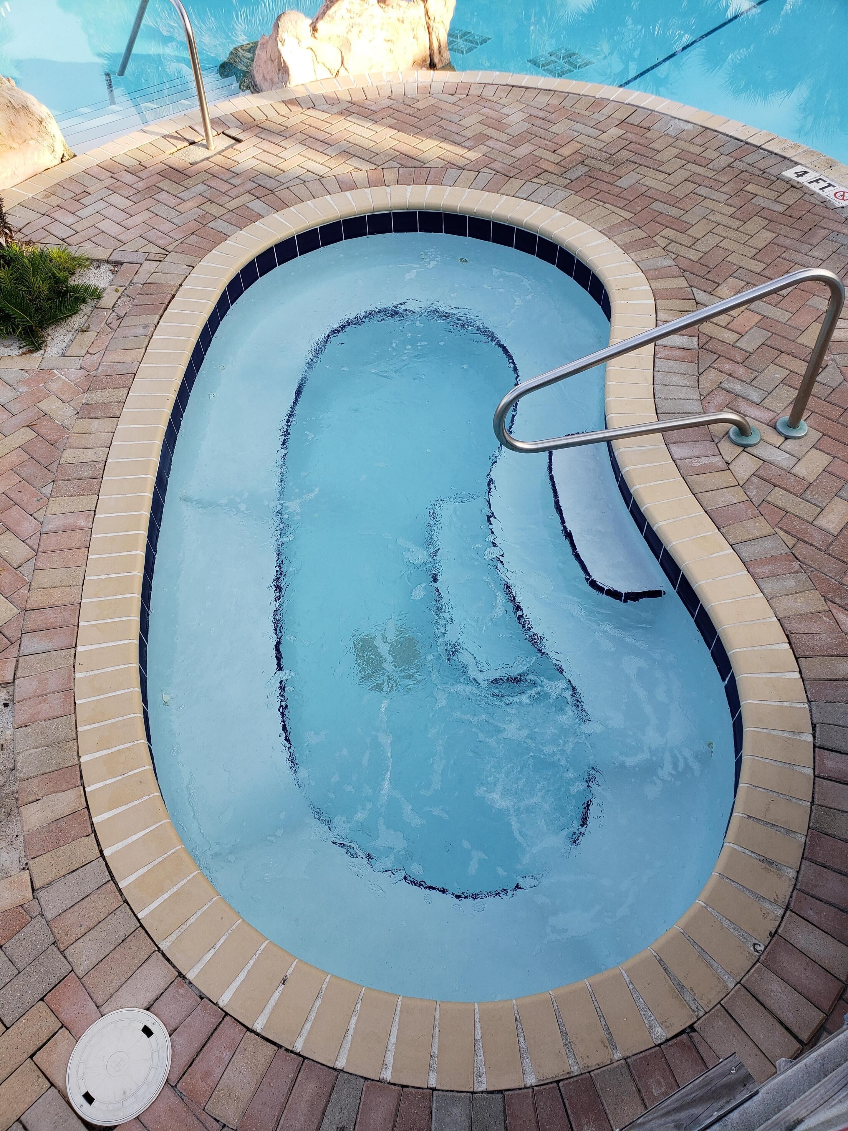 Una piscina con borde de ladrillo y barandillas metálicas.