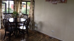 A dining area with a round table and chairs, a potted plant, and a window with curtains. - Cuando el lujo y la comodidad estan rodeados de naturaleza (Los Angeles)