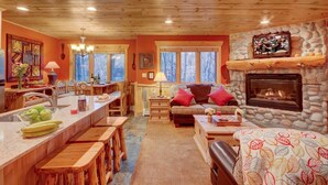 Un interior acogedor con cocina, comedor y sala de estar, con muebles de madera y chimenea de piedra.