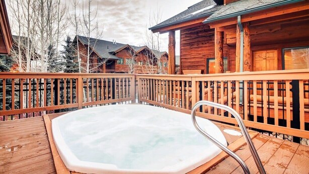 Una terraza de madera con un jacuzzi rodeado por una valla de madera.