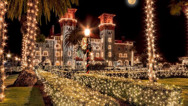 A historic building with illuminated windows and a moon in the sky.