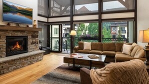 Ein Wohnzimmer mit Kamin, großem Fenster, einer Couch und einem Couchtisch.