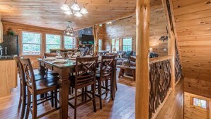 A wooden cabin interior with a dining area, kitchen, and living space. - CROSS CREEK HIDEAWAY | MOUNTAINS | PET FRIENDLY (Sautee Nacoochee)