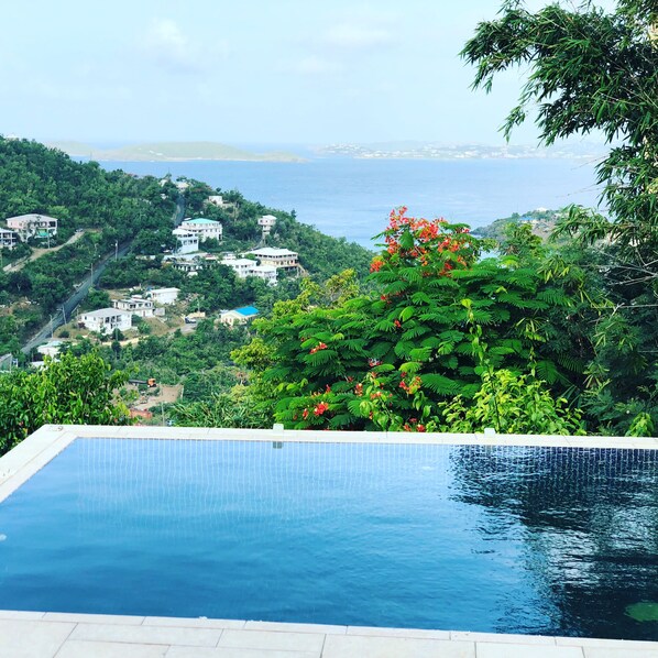 A swimming pool with a view of a coastal landscape and buildings.