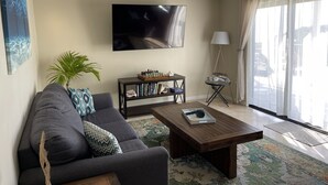 Ein Wohnzimmer mit einer Couch, einem Couchtisch und einem Fernseher an der Wand.