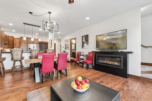 A modern living room with a fireplace, dining area, and kitchen.