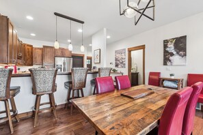 Una cucina moderna con mobili in legno, un grande tavolo da pranzo in legno e sgabelli da bar.