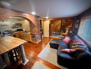 A compact living space with a kitchen, a fireplace, a staircase, and a seating area. - Newly Renovated - Cozy and Quiet Apt Style Cabin on Yellowstone River (Gardiner)