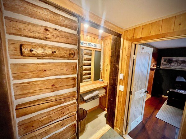 A wooden interior with a log wall, a mirror, and a door leading to another room.