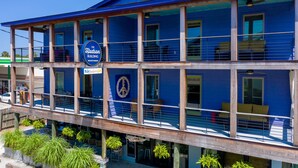 A two-story hotel with a blue exterior, a balcony with seating, and a sign indicating it is The Hudson Building. - Perfect Purple Palace Folly Vacation Apt C (Folly Beach)
