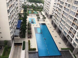 Un edificio de gran altura con piscina, zona de juegos infantiles y jardín en la azotea.