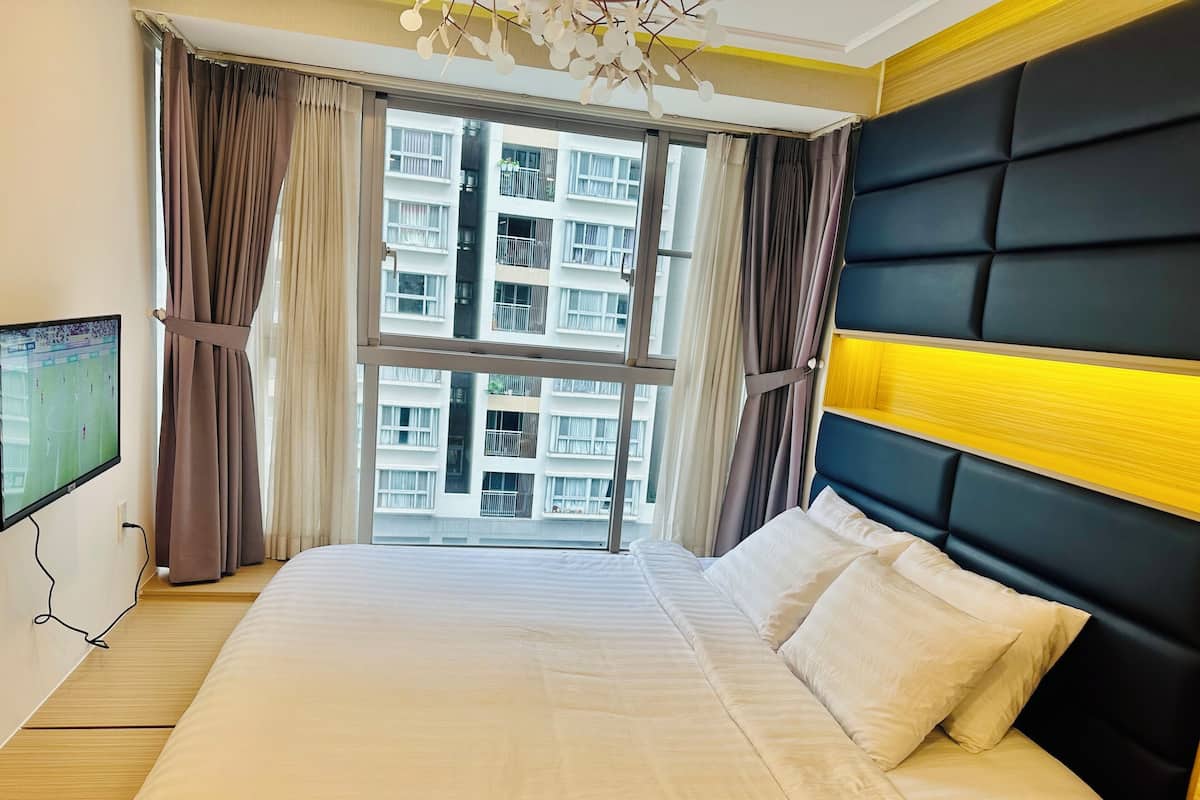 Een hotelkamer met een groot bed, een televisie aan de muur en uitzicht op een gebouw.