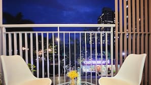 A balcony with two white chairs, a glass table, and a vase with flowers. - Scenic Valley Suite (Ho Chi Minh City)