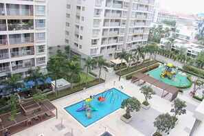 Un edificio residencial con varios balcones, piscina y zona de juegos.