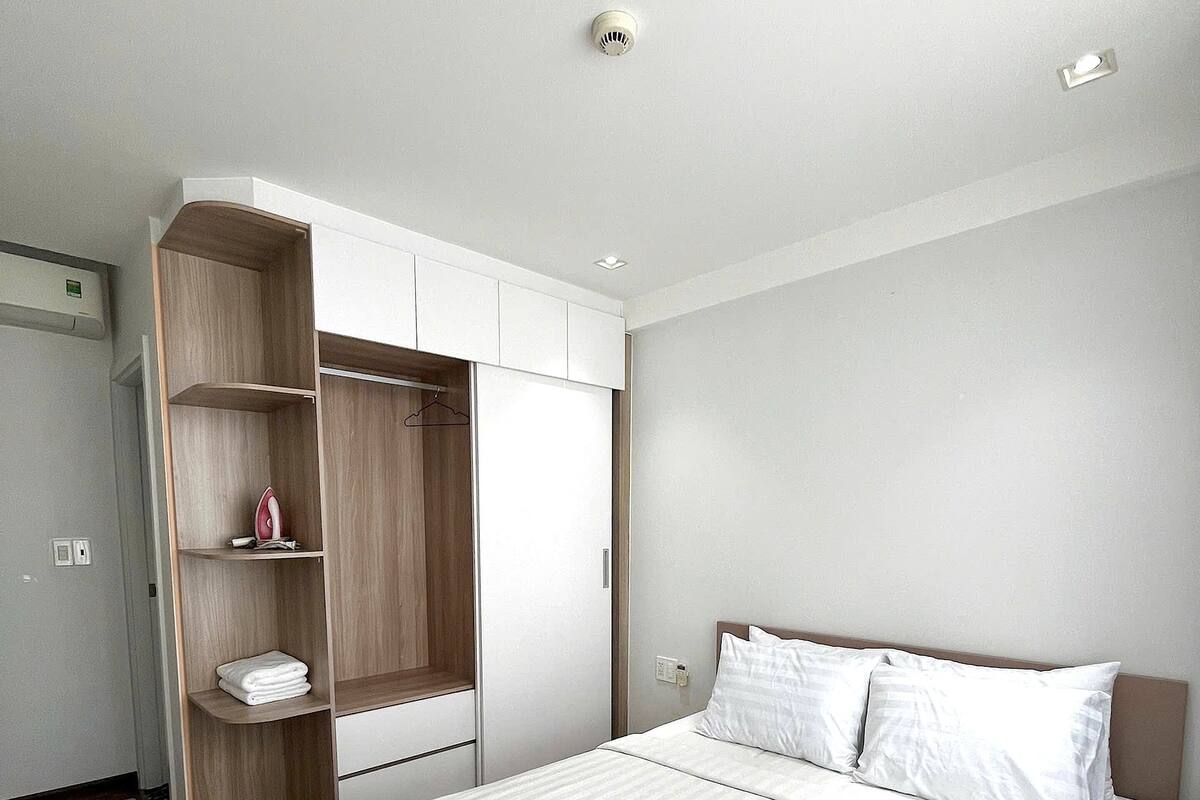 Een moderne slaapkamer met een groot bed, een houten garderobe en een klein plankje.