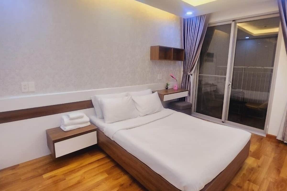 Een moderne slaapkamer met een houten bed, een nachtkastje, een inbouwkast en een schuifdeur naar een balkon.