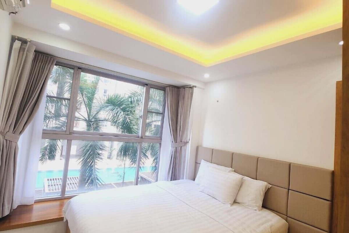 Een moderne slaapkamer met een groot bed, uitzicht op een zwembad en een plafond met inbouwspots.