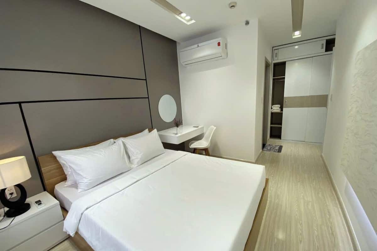 Een moderne hotelkamer met een groot bed, nachtkastje en bureau met stoel.