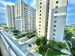 Un edificio residencial de gran altura con varios balcones, un estacionamiento y un patio ajardinado.