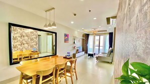 A modern living room with a dining area, large windows, and a view of the cityscape. - Scenic Valley Suite (Ho Chi Minh City)