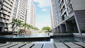 A modern high-rise building with a swimming pool in the foreground. - Scenic Valley Suite (Ho Chi Minh City)