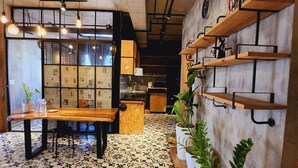 A cozy cafe with a wooden table and chairs, a patterned floor, and shelves with plants and kitchen items. - Scenic Valley Suite (Ho Chi Minh City)
