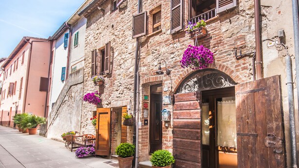 A historic stone building with a wooden door and shutters, potted plants, and a cobblestone street. - B&B Antica Gabella (Castiglione del Lago)
