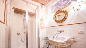 A bathroom with a glass-enclosed shower, a white sink with ornate fixtures, and a decorative mirror. - B&B Antica Gabella (Castiglione del Lago)